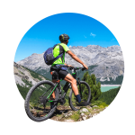 Image of biker taking in a view of the mountains & blue sky