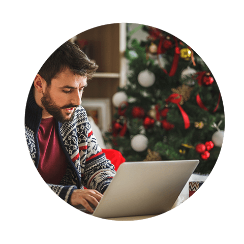 Image of person operating laptop in front of Christmas tree