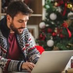Man using computer in front of Christmas tree
