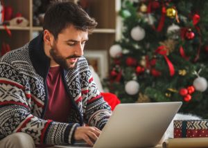 Man using computer in front of Christmas tree