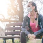 Image of woman wearing facemask on a park bench