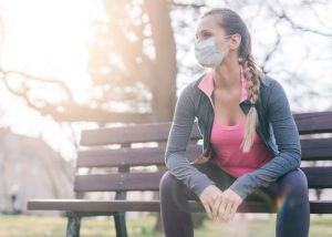 Image of woman wearing facemask on a park bench