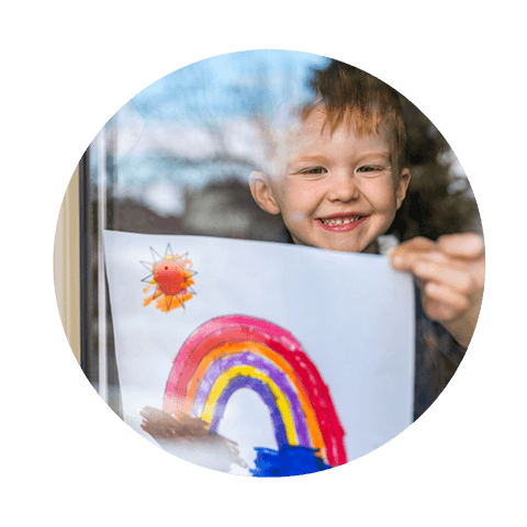 Child smiling with rainbow drawing