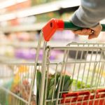 Shopping cart being pushed by customer in supermarket.