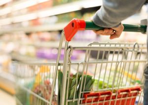 Shopping cart being pushed by customer in supermarket.