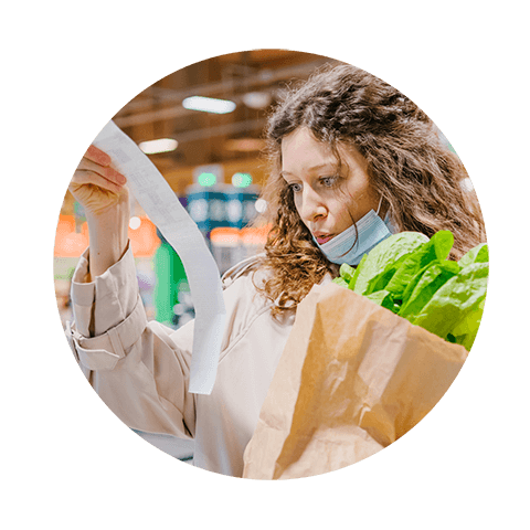 Shopper in supermarket with grocery bag looking at receipt amid the cost of living crisis.